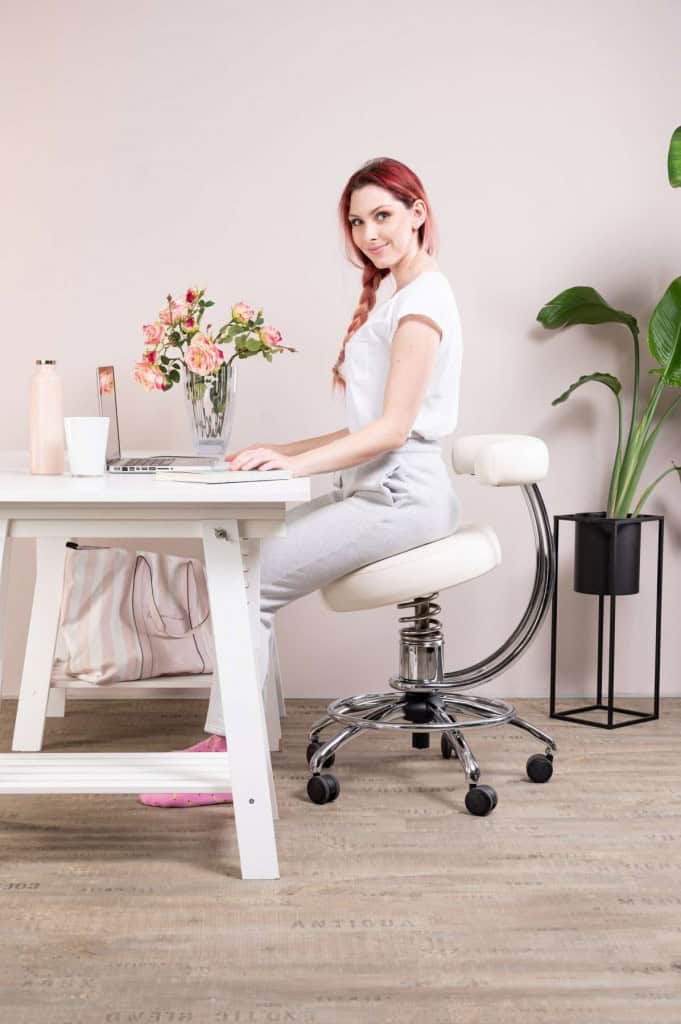 A girl sits on an office chair dent next to a desk